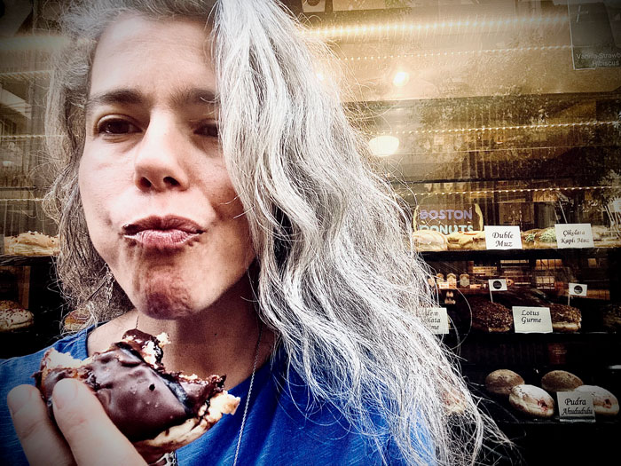 Addiction and Nutrition 2 Addiction and nutrition: A woman eating a chocolate-covered pastry in front of a bakery, representing sugar craving and emotional hunger.