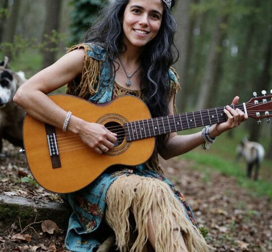 Descubre tu Creatividad con Reiki – Mujer con vestimenta inspirada en pueblos indígenas y corona de gemas, tocando la guitarra en el bosque, simbolizando la expresión creativa libre.
