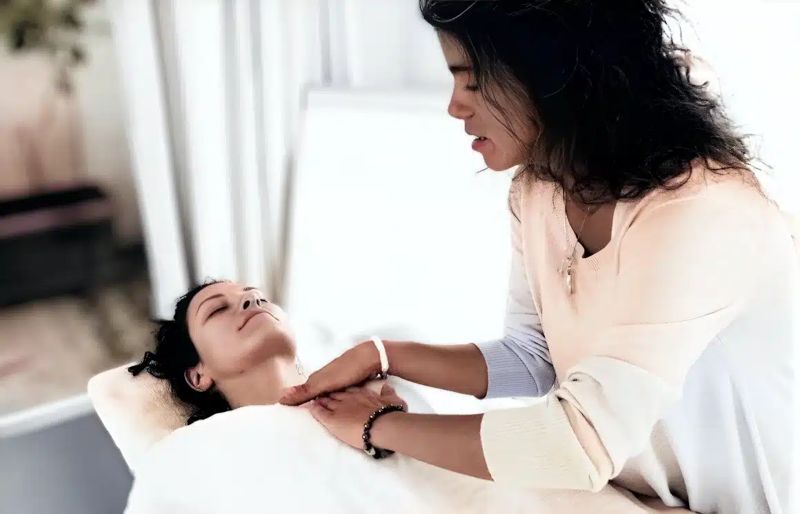 Hande Özerden, who teaches Reiki in London, working with a student at Reiki teacher level, hands on the head and shoulder.