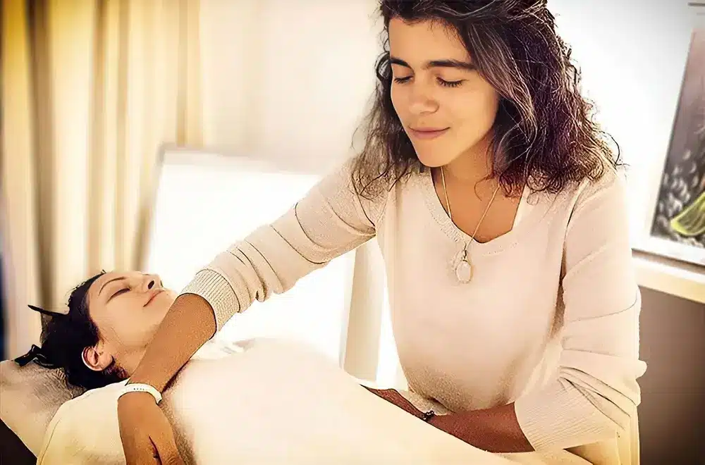 Hande Özerden giving Reiki with her hands resting on a student's head during a Reiki course.